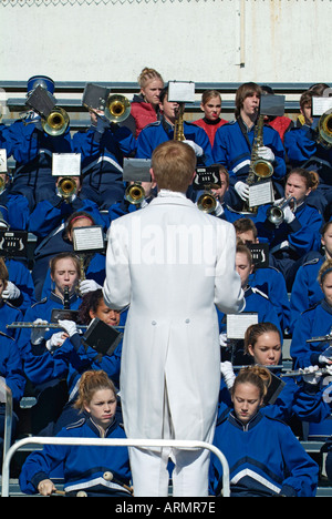 Conductor leads a High school marching band during a football game Stock Photo