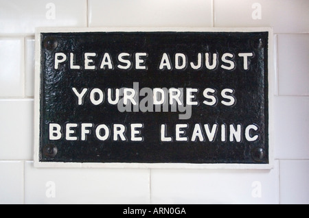 Vintage sign in gents toilet:  Please adjust your dress before leaving.  Or put another way:   Zip up before leaving! Stock Photo