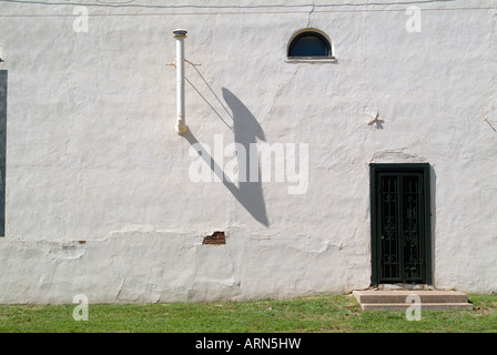 View of a painted wall with door arched window and vent pipe. Stock Photo