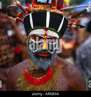 Close up of an Engi Tribesman’s painted face and beard with feathered headband from Papua New Guinea Stock Photo