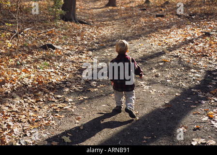 Small Boy walking on trail away alone Stock Photo