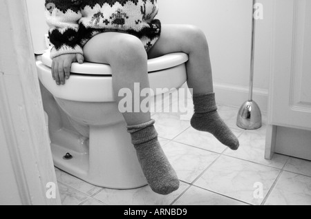 Child Learning to Potty Train Sitting on Toilet Stock Photo