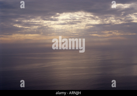 View of calm sea in Lyme Bay with misty winter sunlight and cloud shadows on the water Stock Photo