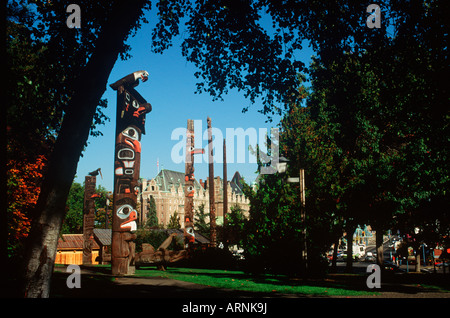 Totem Poles on the grounds of the British Columbian Royal Museum with the Empress Hotel beyond, Victoria, Vancouver Island, Brit Stock Photo