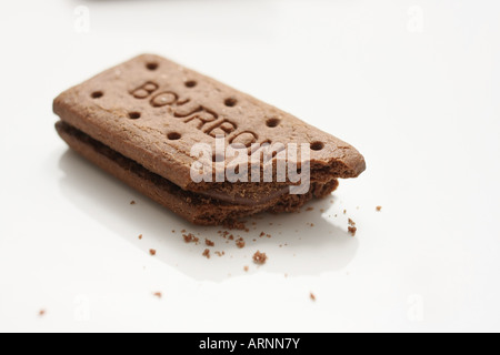 One half-eaten Bourbon biscuit on a white plate Stock Photo