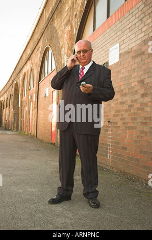 Business man  multitasking using two mobile phones juggling cell phone calls. Stock Photo