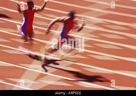 Two runners of a relay team pass the baton. Stock Photo