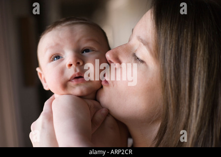 portrait of mother kissing two month old baby boy close up face Stock Photo