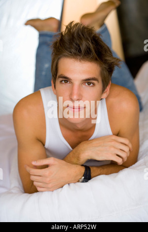 Young man lays on bed portrait Stock Photo