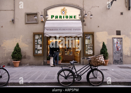 Parione, famous Florentine stationer, in Via Parione, Florence, Tuscany, Italy with a couple looking in the window and a bicycle Stock Photo