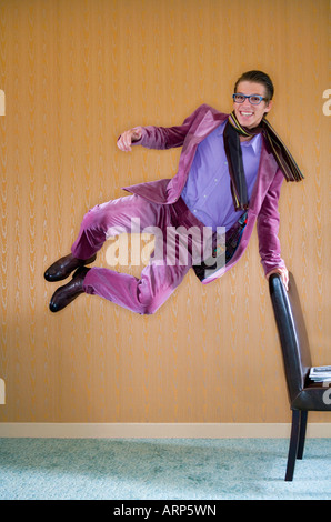 Young man in purple suit jumps for joy Stock Photo