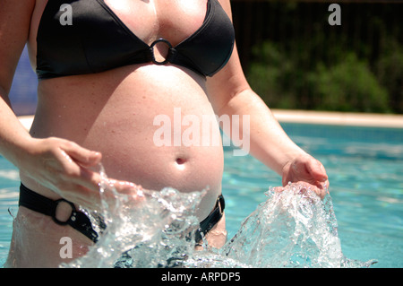 Pregnant woman splashing in swimming pool Stock Photo