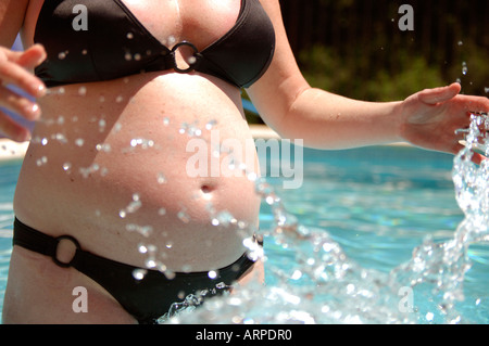 Pregnant woman splashing in swimming pool Stock Photo