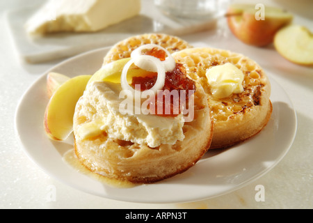 Serving of hot buttered Crumpets with wensleydale cheese and onion pickle on a white plate in a table setting Stock Photo