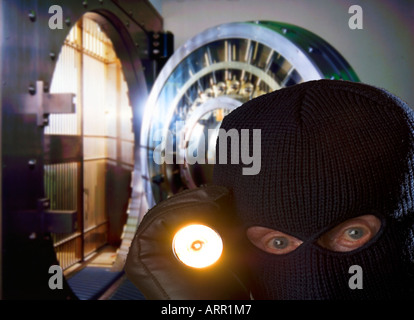 bank robber with ski mask and flashlight in bank vault Stock Photo