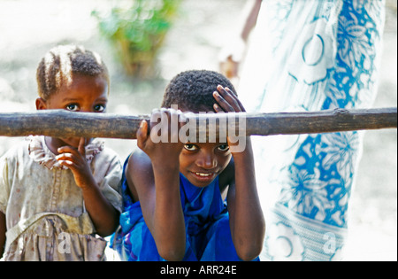 AFRICA KENYA KALIFI Young Kenyan girls play peek a boo with visitors as mother stands by dressed in traditional kanga cloth Stock Photo