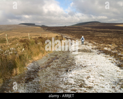Walker on a track in Dartmoor, England, with a light covering of snow Stock Photo