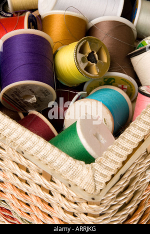 The concept of sewing and embroidery is highlighted by colorful spools of thread in a sewing basket