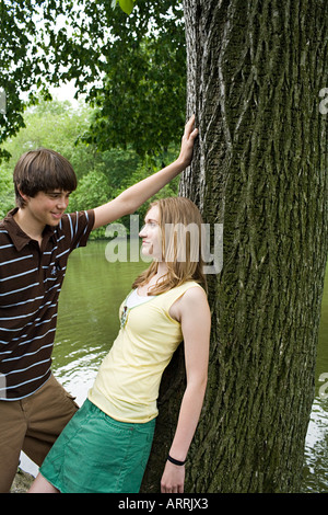 Teenage couple flirting near a tree Stock Photo