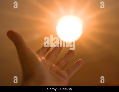 Hand reaching for sun Stock Photo