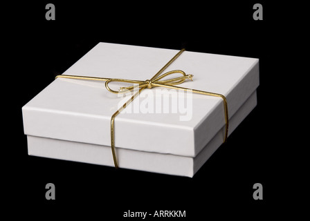 A beautiful white gift box with gold bow isolated against a black background Stock Photo