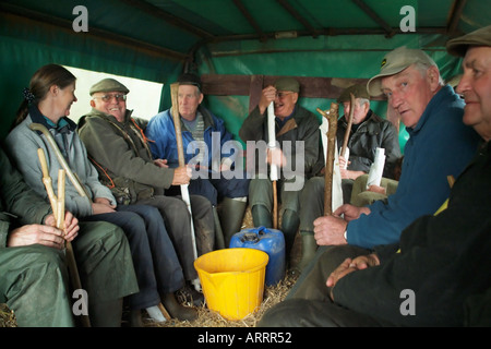 Beaters seated on tractor trailer being transported to their beating location for the days shoot Stock Photo
