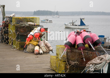 Lobster pots with brightly coloured buoys sit on the dock on a foggy day at Little Cranberry,Maine, USA. Stock Photo