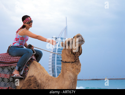 Western woman riding a camel on the beach in Dubai, United Arab Emirates Stock Photo