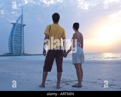 Western couple looking at Burj Al Arab hotel from the beach, Dubai, UAE