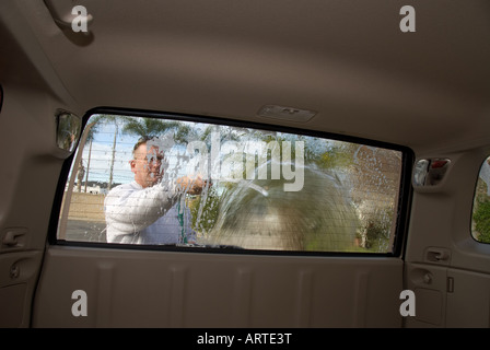 A man is engaged in washing his SUV on a bright sunny day Stock Photo