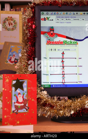 A computer screen decorated with tinsel displaying a Christmas-themed page from the ebay web site with Christmas cards. 2005. Stock Photo