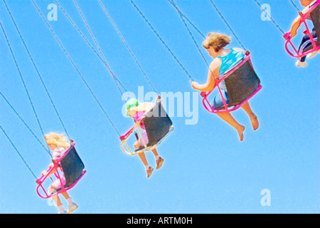 Digitally modified photo of children flying in the air on seats hanging from chains on a spinning swings ride Stock Photo