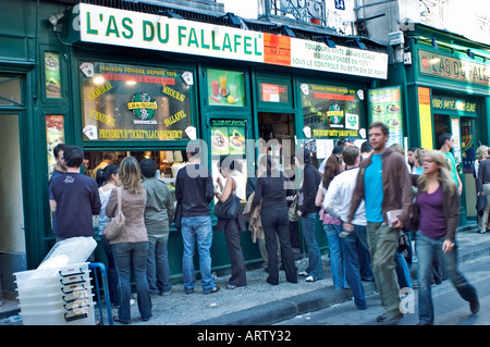 PARIS France, Crowd People, Adults Standing on Line Outside French Kosher 'Jewish Restaurant' on 'L'As du Fallafel' Queue Sidewalk Eating Stock Photo