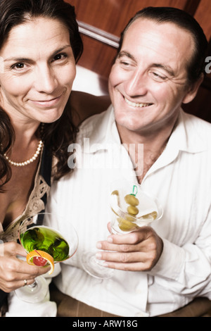 Mid adult couple holding glasses of cocktail and smiling
