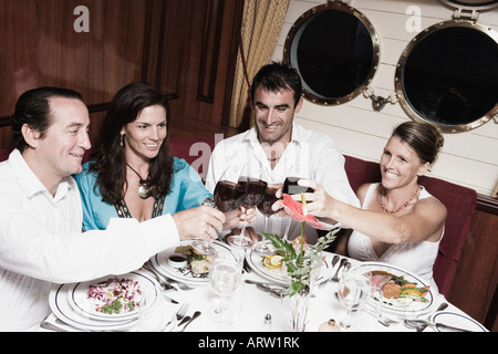 Two mid adult couples toasting with wine glasses and smiling Stock Photo