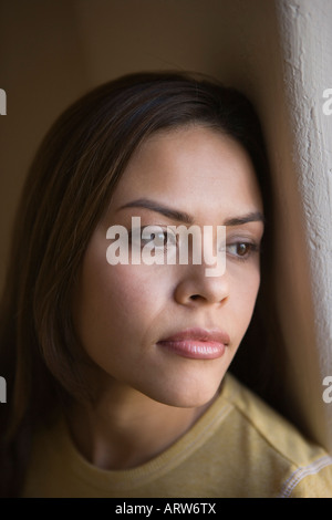 young woman looking towards window with an expression of longing Stock Photo