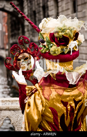 A woman in mask and Carnival Costume standing on the Bridge of Sighs Venice Italy looking at her reflection in a hand mirror Stock Photo