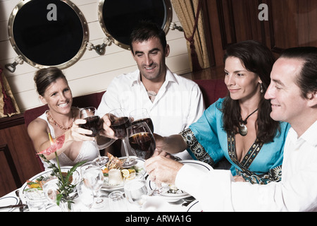 Two mid adult couples toasting with wine glasses and smiling Stock Photo