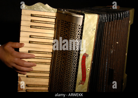 A creepy false hand plays an old broken Accordion. Stock Photo