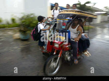 Children ride a tricycle taxi to school in Mansalay, Oriental Mindoro, Philippines. Stock Photo