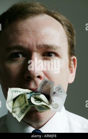 Man with money stuffed in his mouth Stock Photo