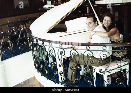 Portrait of a mid adult man playing a piano with a mid adult woman smiling beside him Stock Photo