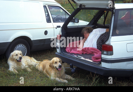 Who's sleeping in OUR bed??? At a dog show the owner takes over the dog's bed in the boot of her car. Stock Photo