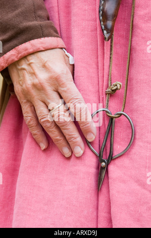 Weathered hand with scissors from the 1600's on handmade pink cloth, an English colonial seamstress reenactor. Stock Photo