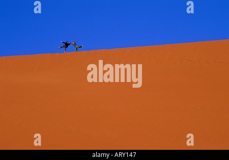 Tourists having fun while climbing a dune in the desert of Wadi Rum, in ...