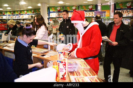 A Santa shops for cigarettes during a gathering of Santas at Victoria Station in London December 2004 Stock Photo