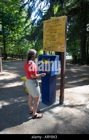 Woman paying parking fee in coin operated machine Sproat Lake Vancouver island Canada Stock Photo