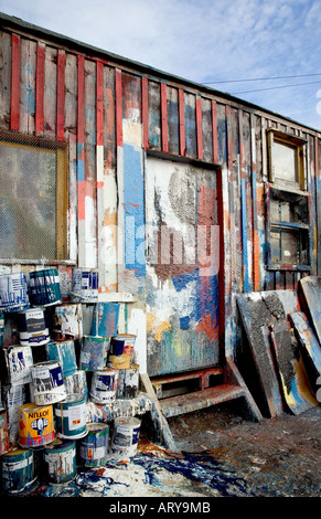 Boat repairers paint shed outdoor building, test colour daubs, brush marks, and paint tins at Banff fishing boat repair yard North East Scotland UK Stock Photo