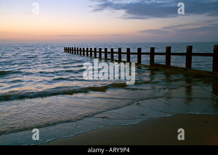 Beach and breakwater at dusk with wind farm on horizon Rhyl North Wales UK Stock Photo