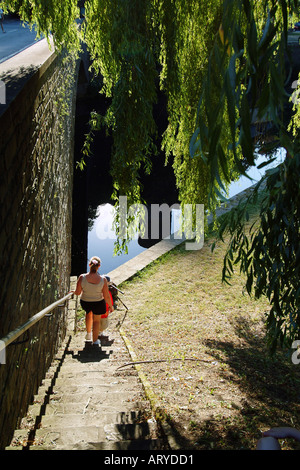 woman walking down steps sun sunlit trees Stock Photo